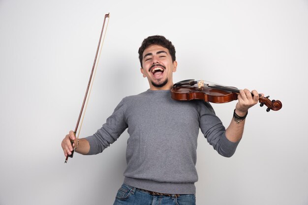 O músico toca violino e parece inspirado e positivo.