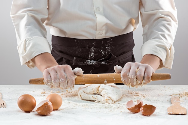 O padeiro fazendo pão, amassando uma massa