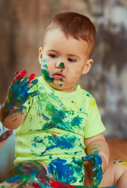 O pequeno bebê pintando as mãos