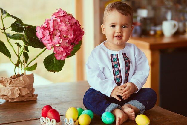 O pequeno bebê senta-se perto de ovos de Páscoa