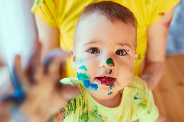 O pequeno bebê tem tinta no rosto