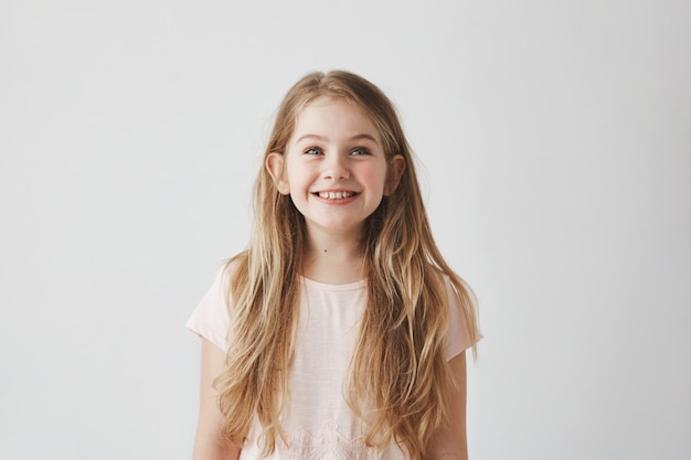 O retrato da menina bonito com cabelo claro longo que sorri olhando de cabeça em balões coloridos do voo com expressão feliz e entusiasmado.