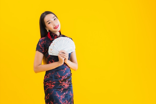 O retrato da mulher asiática nova bonita veste o vestido chinês e prende muito dinheiro