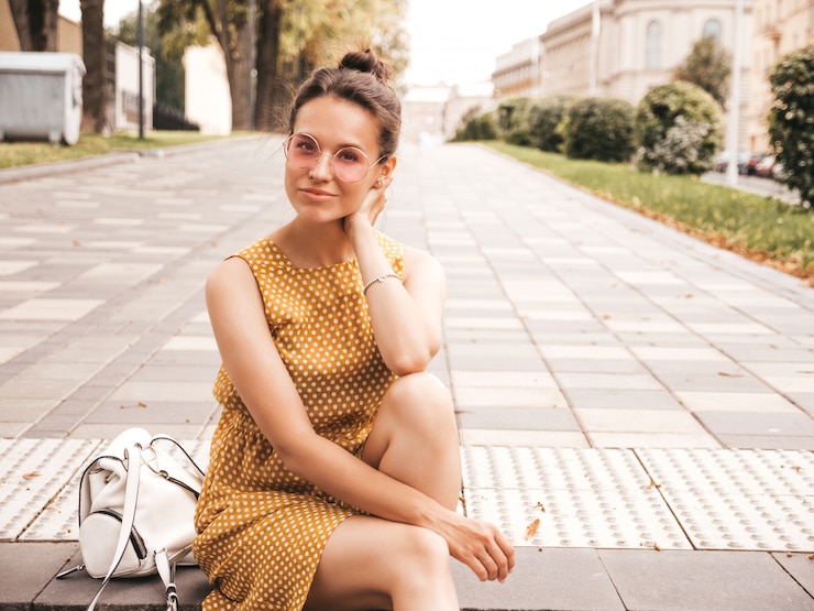 Foto grátis o retrato do modelo de sorriso bonito do moderno vestiu-se no vestido amarelo do verão. menina na moda posando na rua. mulher engraçada e positiva se divertindo