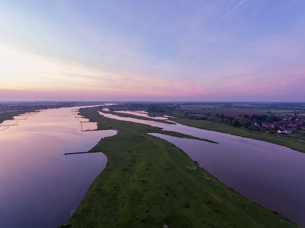 O rio Lek cercado pela vila de Everdingen durante um belo pôr do sol na Holanda