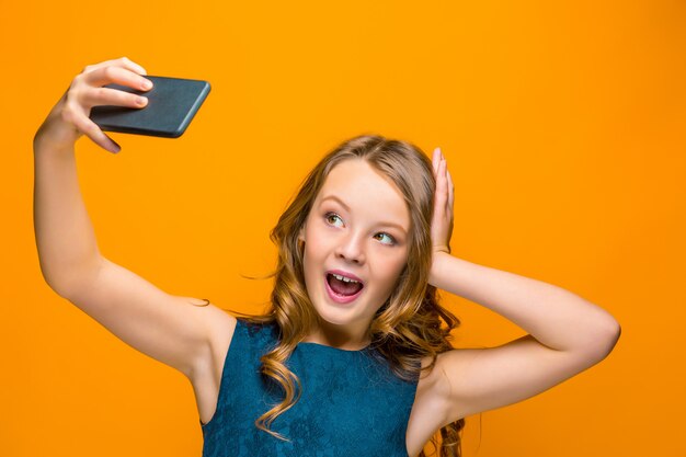 O rosto da menina adolescente feliz brincalhão com telefone