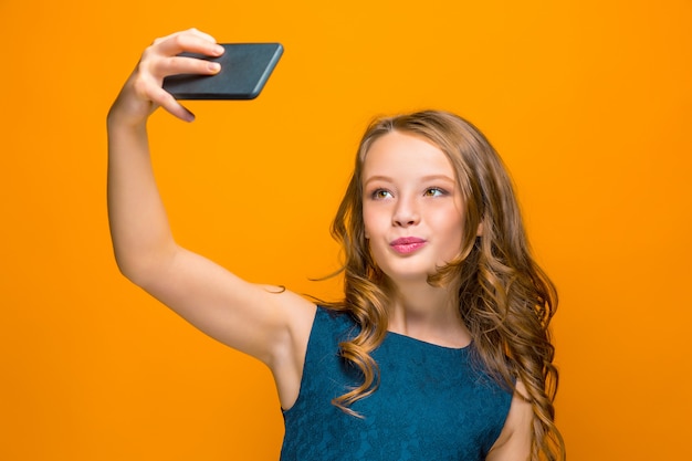 O rosto da menina adolescente feliz brincalhão com telefone