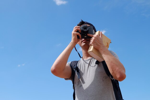 O viajante do jovem homem está tirando fotos com o guia, o conceito de viagem e recreação.