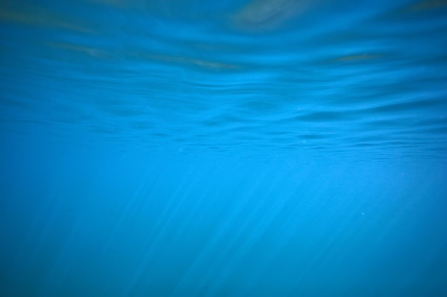 Oceano água fundo azul raios subaquáticos sol / fundo azul abstrato natureza água