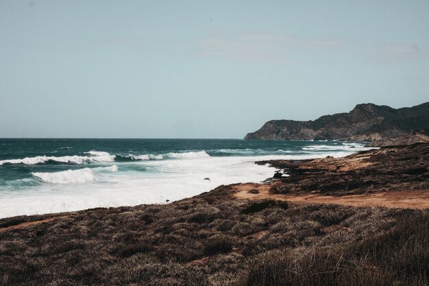 Oceano ondulado com formações rochosas sob o céu azul