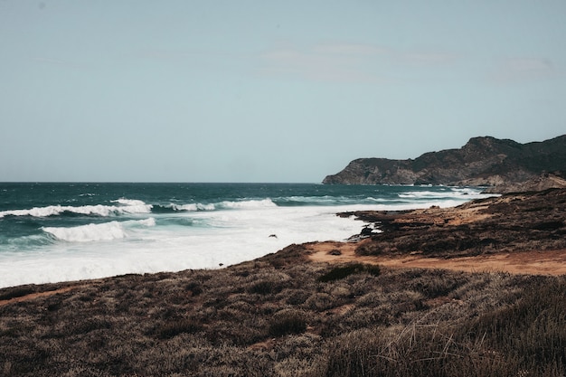 Oceano ondulado com formações rochosas sob o céu azul