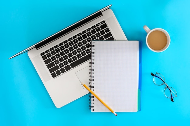 Óculos de laptop e xícara de café em um fundo azul