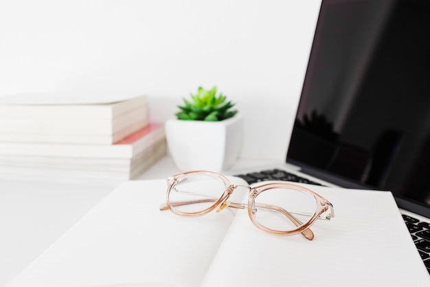 Óculos; notebook e laptop na mesa de escritório