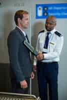 Foto grátis oficial de segurança do aeroporto usando um detector de metais portátil para verificar um passageiro