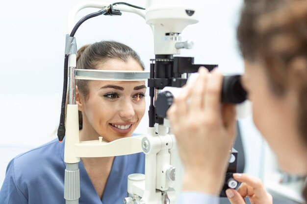 Oftalmologista com paciente do sexo feminino durante um exame na clínica moderna Oftalmologista está usando equipamento médico especial para saúde ocular