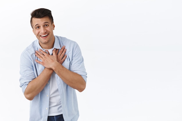 Oh tão doce. retrato de um homem caucasiano bonito lisonjeado e satisfeito, curvando-se e agradecendo pelo lindo presente adorável, pressione as mãos no coração e sorrindo, grato por elogios e elogios