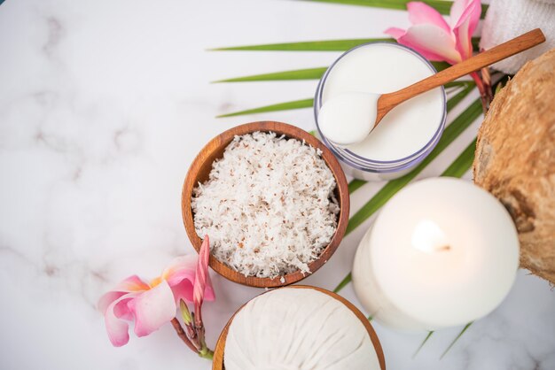 Óleo de coco, folhas tropicais e cocos frescos. Produtos de coco spa na superfície de madeira clara.