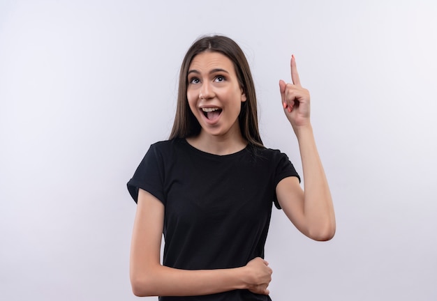 Olhando para a alegre jovem caucasiana, vestindo uma camiseta preta com o dedo apontando para cima