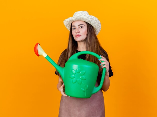 Olhando para a câmera, a bela jardineira vestindo uniforme e chapéu de jardinagem