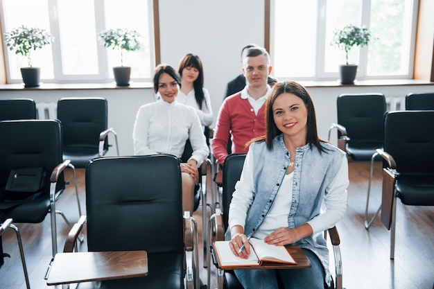 Olhando para a câmera. Grupo de pessoas em conferência de negócios em sala de aula moderna durante o dia