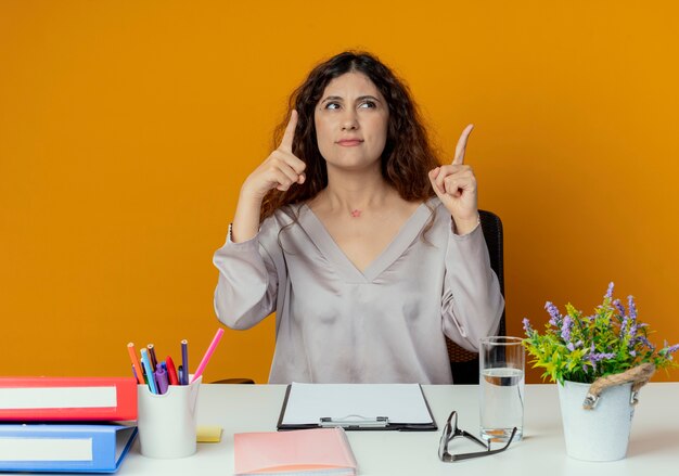 Olhando para uma jovem e bonita trabalhadora de escritório confusa sentada na mesa