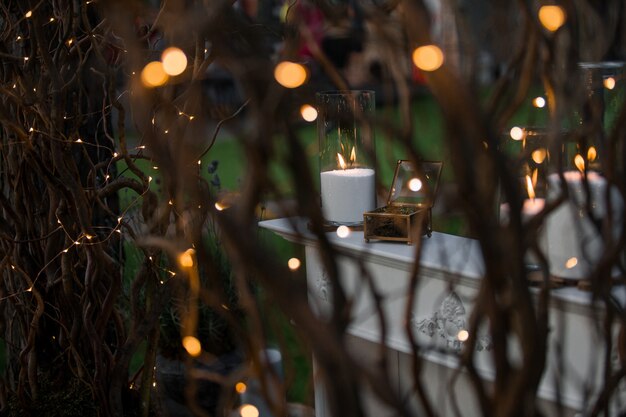 Olhe através dos ramos brilhantes na mesa branca com velas