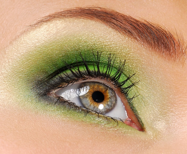 Olhos de mulher com cor verde brilhante de cosmético para sombra