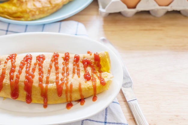 Omelete com ketchup no topo em um prato branco com uma bandeja de ovo borrão como pano de fundo