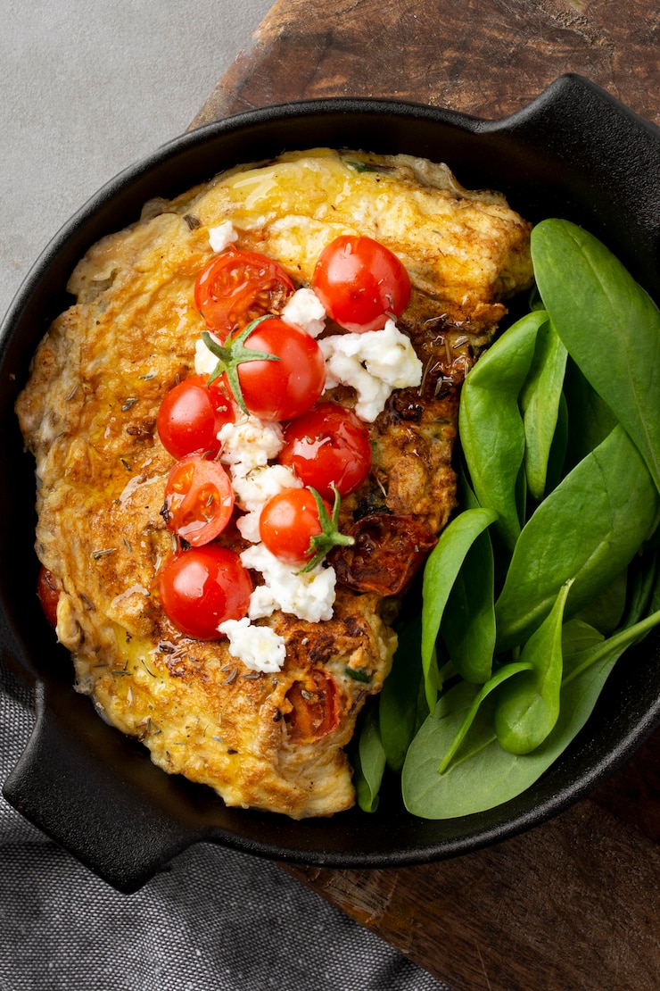 Foto grátis omelete de cima com folhas e tomates