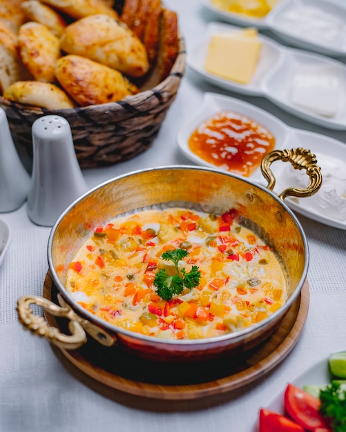 Omelete de vista superior com legumes em uma panela com uma cesta de pão