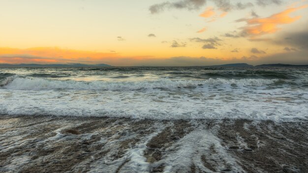 Ondas do mar batendo na praia durante o pôr do sol