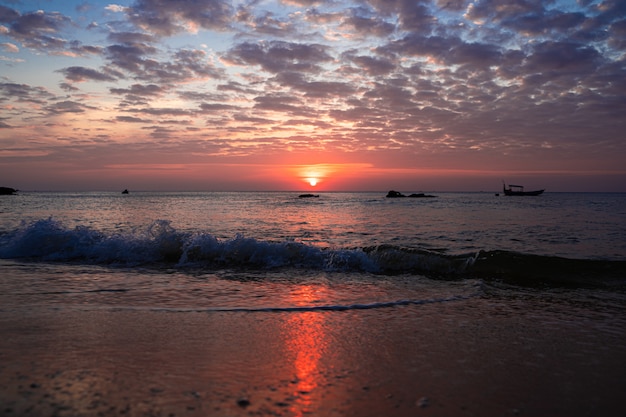 Ondas que chegam na praia durante um pôr do sol