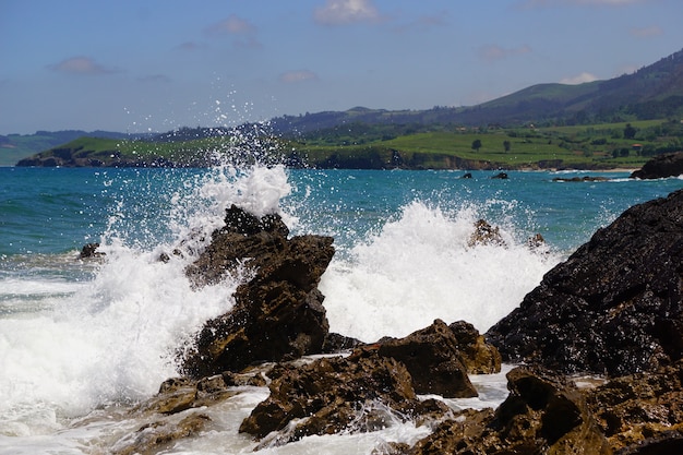 Ondas quebrando em rochas com um oceano azul atrás delas