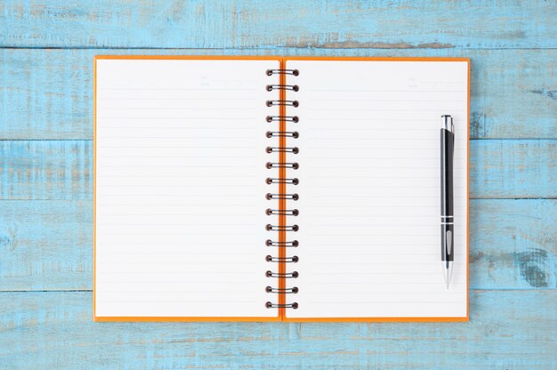 Open orange Notebook e caneta na mesa de madeira azul