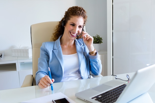 Operador do serviço ao cliente falando no telefone no escritório.