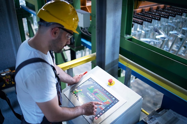 Operário de fábrica monitorando máquinas industriais e produção remotamente na sala de controle