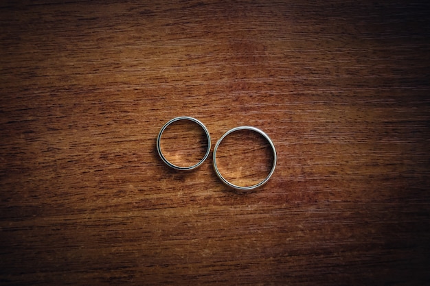 Os anéis de casamento de prata ficam na mesa de madeira