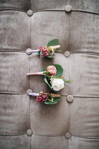 Os boutonnieres cor-de-rosa encontram-se no sofá cinza