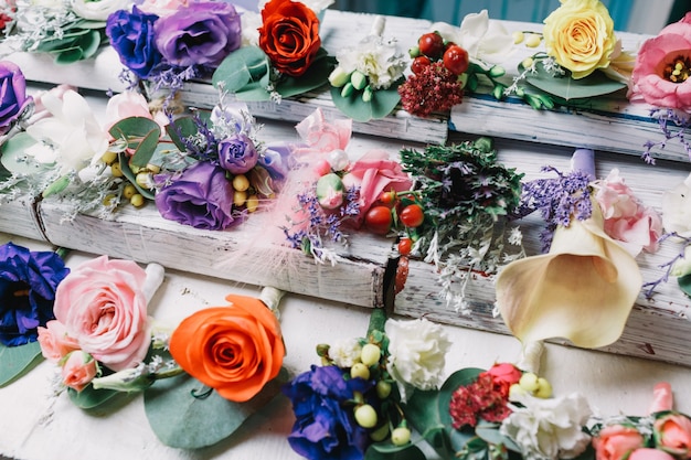 Os boutonnieres violetas estão entre os outros na mesa branca