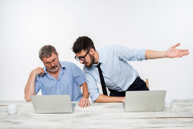 Os dois colegas trabalhando juntos no escritório em fundo branco. Eles estão discutindo algo. ambos estão olhando para uma tela de computador