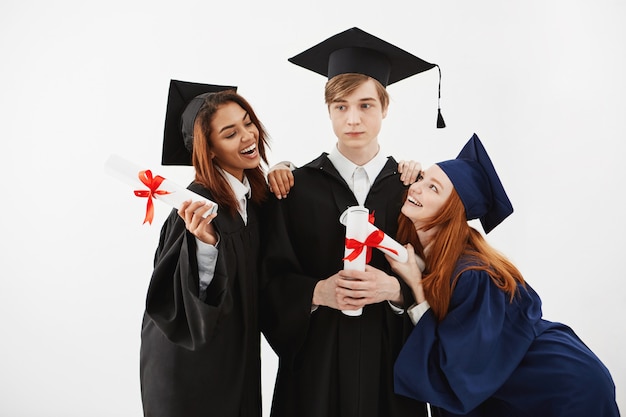 Os estudantes internacionais graduam-se alegrando posando posando.