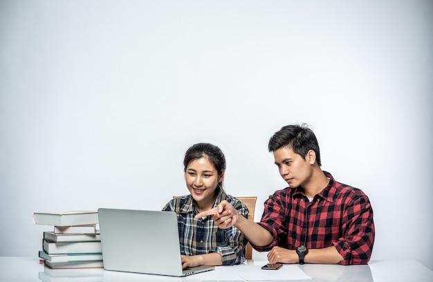 Os homens ensinam as mulheres a trabalhar com laptops no trabalho.