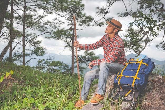 Os homens sentam e observam montanhas em florestas tropicais com mochilas na floresta. Aventura, viajar, escalar.