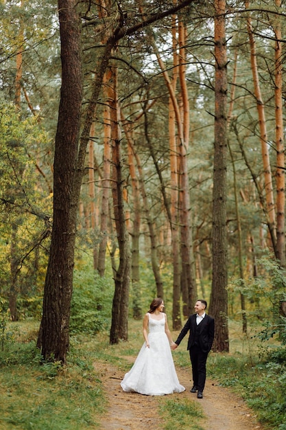 Os noivos correm por uma floresta Sessão de fotos de casamento