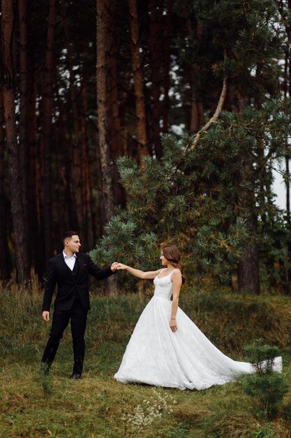 Os noivos correm por uma floresta Sessão de fotos de casamento