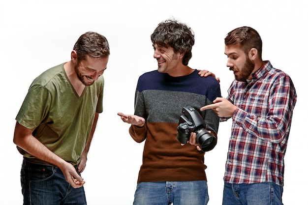 Os três amigos do sexo masculino com câmera em branco
