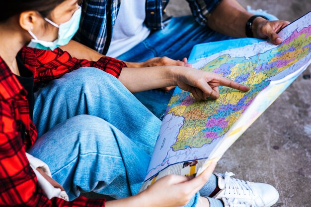 Os turistas masculinos e femininos olham para o mapa ao lado da ferrovia.