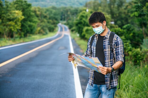 Os turistas masculinos estão e olham para o mapa na estrada.