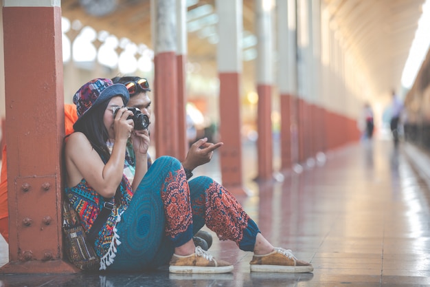 Os viajantes tiram fotos de casais enquanto esperam por trens.