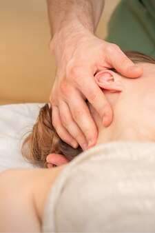 Osteopata fazendo massagem na cabeça feminina no centro da clínica de reabilitação.